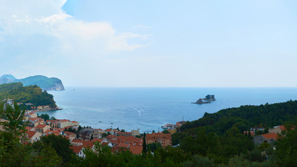 View from a high point on the Bay of Kotor with two islands in the sea against the background of the mountain and traces of water from a jet ski.