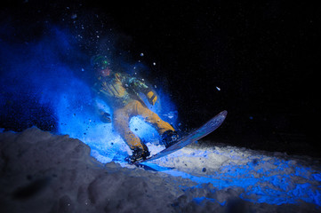 Active male snowboarder dressed in a yellow sportswear performs tricks on the snow slope