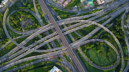 4K. Aerial view of road interchange or highway intersection with busy urban traffic speeding on the road. Junction network of transportation taken by drone. - Powered by Adobe