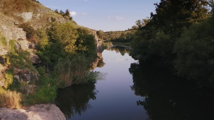 Aerial shot with drone flying close to the water in canyon during sunny day