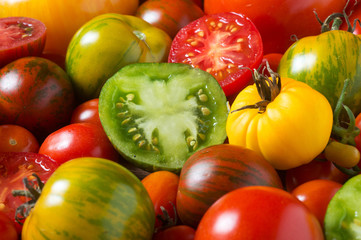 Close up of colorful tomatoes, some sliced, shot from above