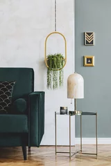 Fotobehang Boho Stylish and luxury interior design of living room with green velvet sofa, design coffee table, marble table lamp, hanging gold flowerbed and elegant accessories. Template. Modern home decor.   © FollowTheFlow