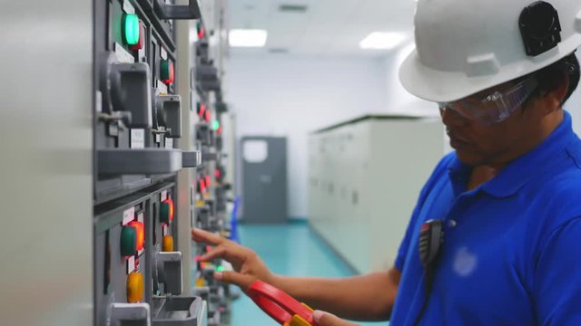 Engineer working in electricity substation building for check electrical control equipment by ampmeter , Industrial and technology concept