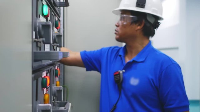 Engineer working in electricity substation building for check electrical control equipment by ampmeter , Industrial and technology concept