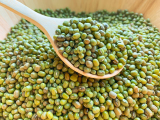 closeup of any mungbean or green beans on a wooden spoon in a wooden bowl