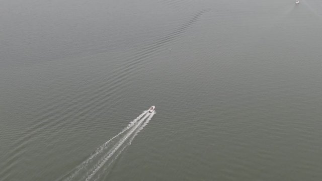 White boat sails at sea and splashing waves. Drone shot. Motorboat. Flying over ocean water.