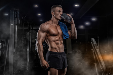 Fototapeta na wymiar A young handsome man with big muscles, holds a shaker with protein, rest after cross-training