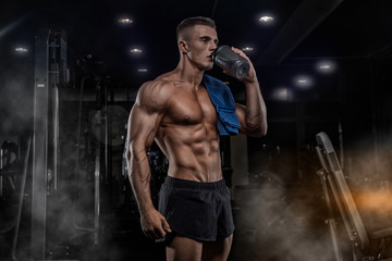 A young handsome man with big muscles, holds a shaker with protein, rest after cross-training