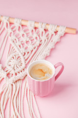 Creative flat lay concept, coffee cup and macrame panel on pastel pink background and copy space, minimal style, saint valentine romance trendy composition