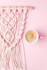 Creative flat lay concept, coffee cup and macrame panel on pastel pink background and copy space, minimal style, saint valentine romance trendy composition