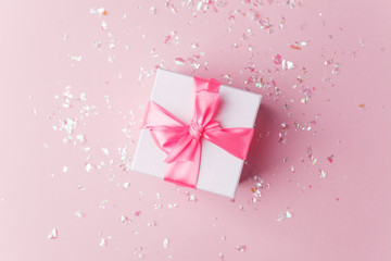 White gift box and confetti on pink background with copy space for text. fashion and shopping concept. wedding, marriage or birthday composition. flat lay, top view