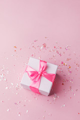 White gift box and confetti on pink background with copy space for text. fashion and shopping concept. wedding, marriage or birthday composition. flat lay, top view