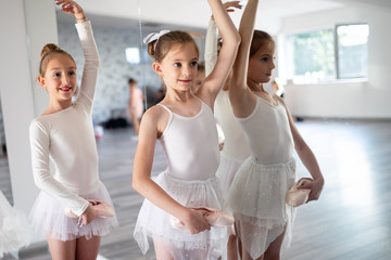 Group of fit happy children exercising ballet in studio together