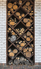 Exterior in yard. Decorative stacks of firewood in numerous nests of square shaped in the wall. 