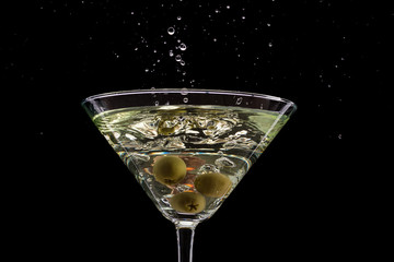 a glass of martini and a splash from falling olives