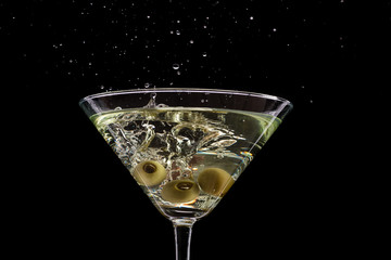 a glass of martini and a splash from falling olives