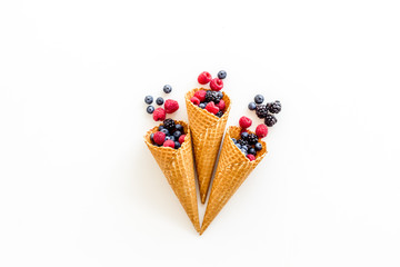 Fresh berries in waffle cones on white background top view