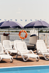 white sunbeds by the pool on a background of water. summer rest. Hot Summer