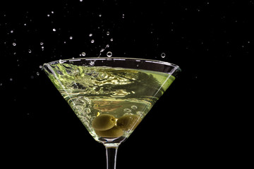 a glass of martini and a splash from falling olives