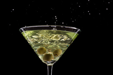 a glass of martini and a splash from falling olives