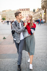 Happy loving couple smiling and walking throug the main square in Krakow (Cracow)