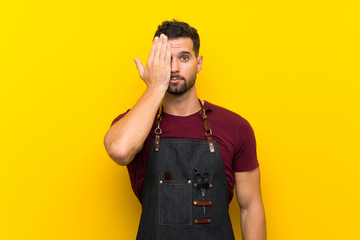 Barber man in an apron covering a eye by hand