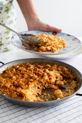 man serving a spanish chicken paella