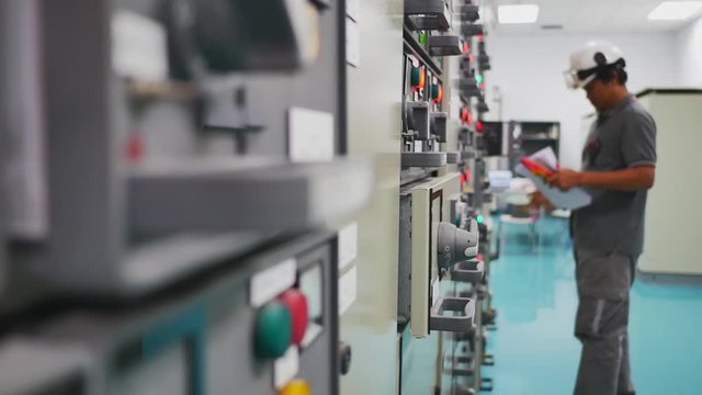 Engineer working in electricity substation building for check electrical control equipment by ampere meter , Industrial and technology concept