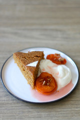 Slice of homemade sponge cake served on a table with whipped cream, cooked apricots and walnuts. Selective focus.