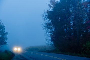 Car on a lonely foggy road in the early morning, Stowe, Vermont, USA