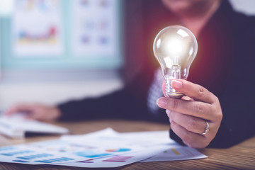Asian businesswoman hand hold light bulbs at home office desk background.,Concept idea and innovation.