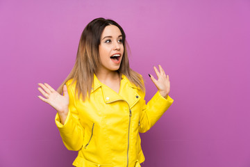Young woman over purple background with surprise facial expression