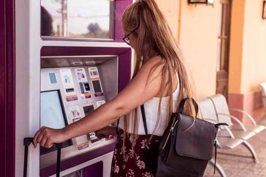 Blonde Girl With Backpack Buying Train Tickets At An Automatic Machine At The Station