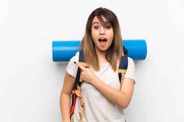 Young traveler woman over white background surprised and pointing side