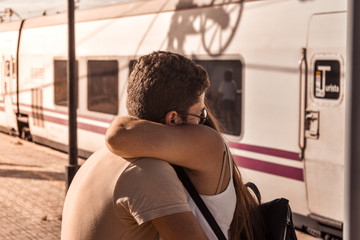 Young couple hug each other to say goodbye before leaving on the train