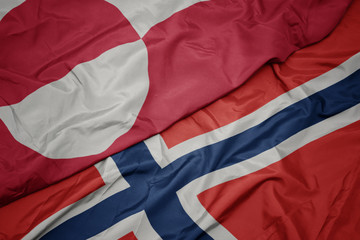 waving colorful flag of norway and national flag of greenland.