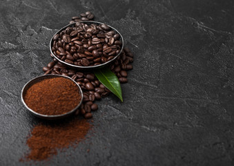 Fresh raw organic coffee beans with ground powder and coffee trea leaf on black background.