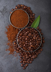 Fresh raw organic coffee beans with ground powder and coffee trea leaf on black background.