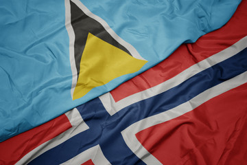 waving colorful flag of norway and national flag of saint lucia.