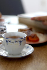 Cup of coffee and slice of homemade sponge cake served on a table with whipped cream, cooked apricots and walnuts. Selective focus.