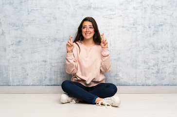 Teenager student girl studying in a table with fingers crossing and wishing the best