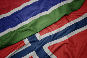 waving colorful flag of norway and national flag of gambia.