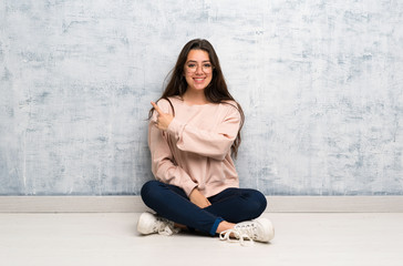 Teenager student girl studying in a table pointing to the side to present a product