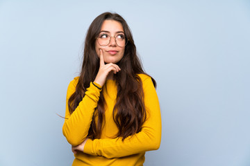 Teenager girl over isolated blue wall thinking an idea