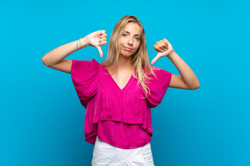Fototapeta premium Blonde young woman over isolated blue background showing thumb down