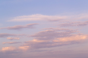 Obraz premium Purple clouds in the sunset. Air clouds in the blue sky. The sun's rays pass through the clouds. Nature background .
