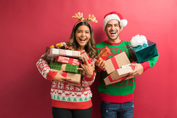 Latin couple with ugly sweaters and a lot of christmas gifts