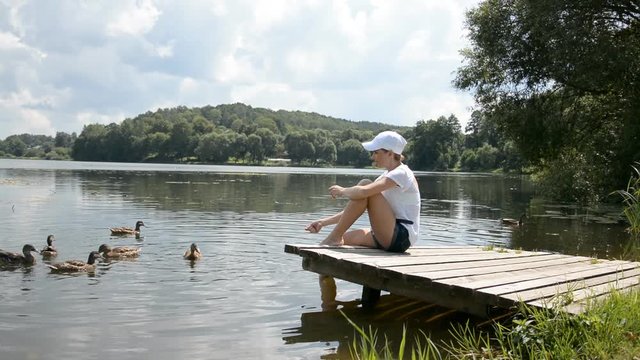 beautiful girl feeds a waterfowl of ducks and swans in a pond on a beautiful summer day hd stock footage