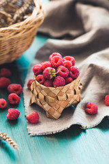 Fresh raspberries in a basket on a green wooden background. Rustic style