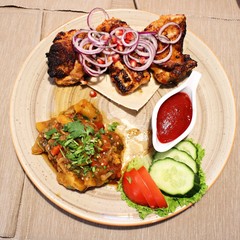 Grilled chicken stewed potatoes fresh onions tomatoes cucumbers and ketchup